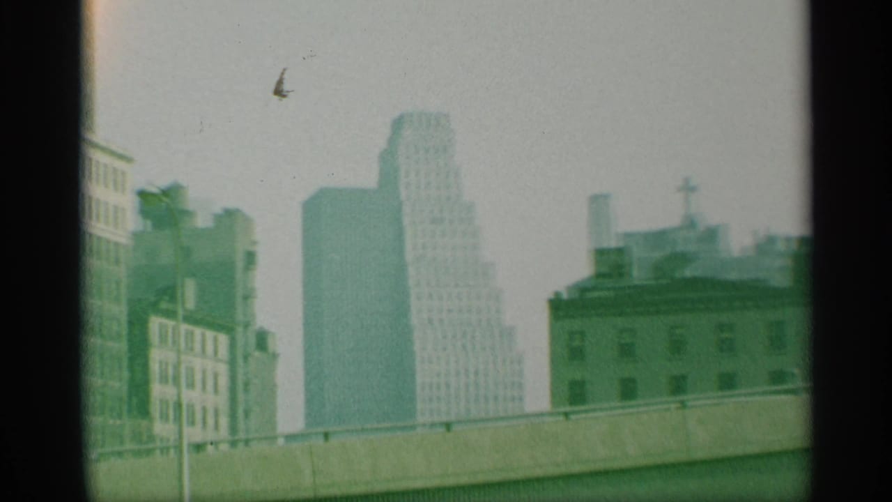 Hazy city skyline with tall buildings under a pale sky.