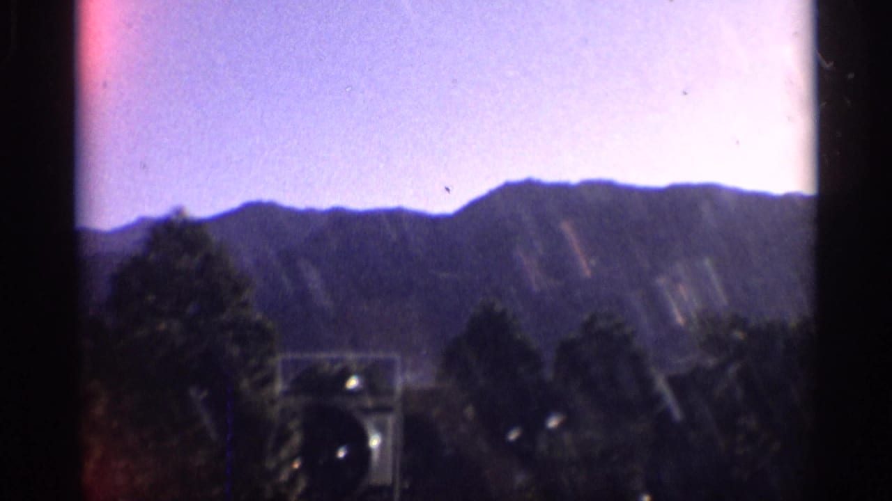 Distant hills and trees seen through dark 8mm film borders.