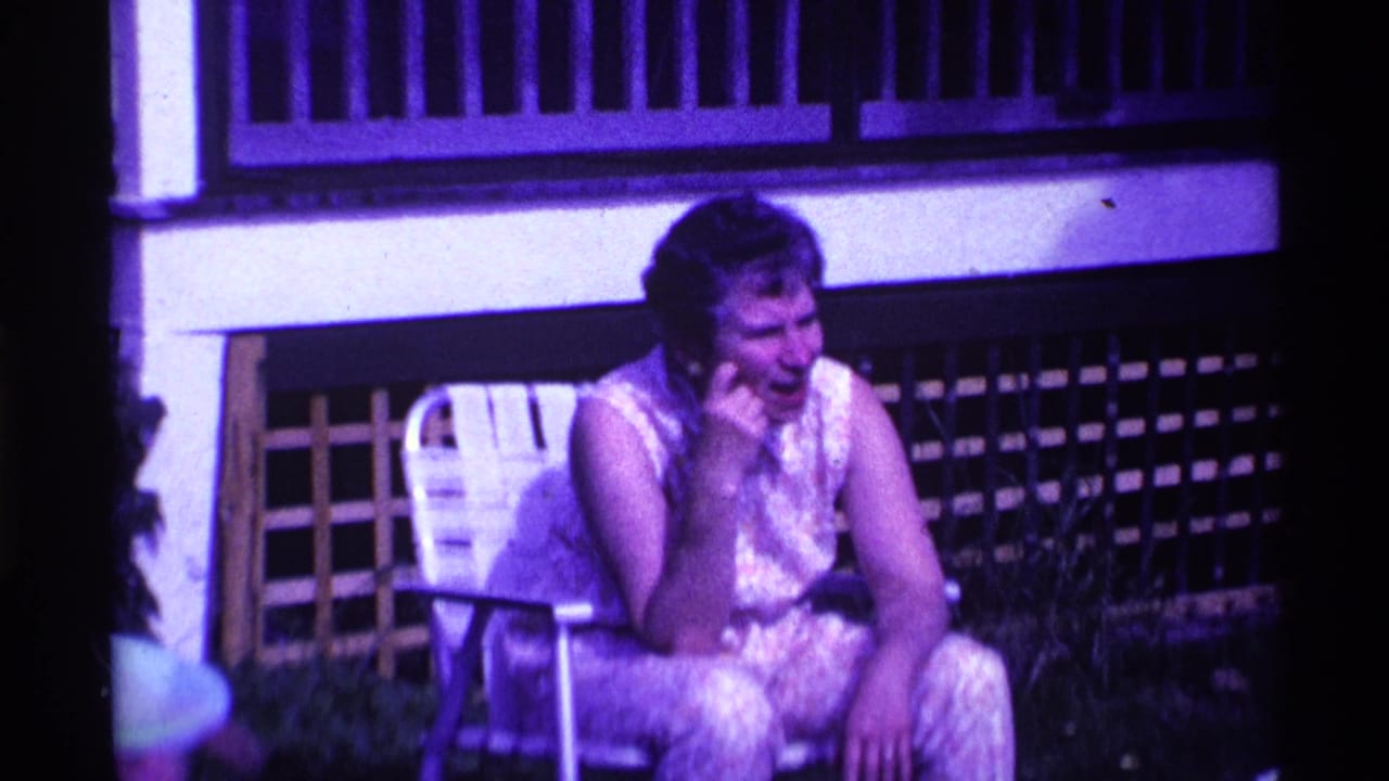 Woman seated in a lawn chair near a porch, resting her head on her hand.