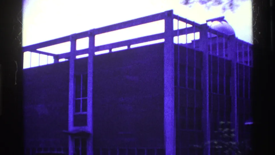 1969 Ohio 8mm frame showing a blue-tinted modernist building exterior with vertical supports, tall windows, and dark edge framing.
