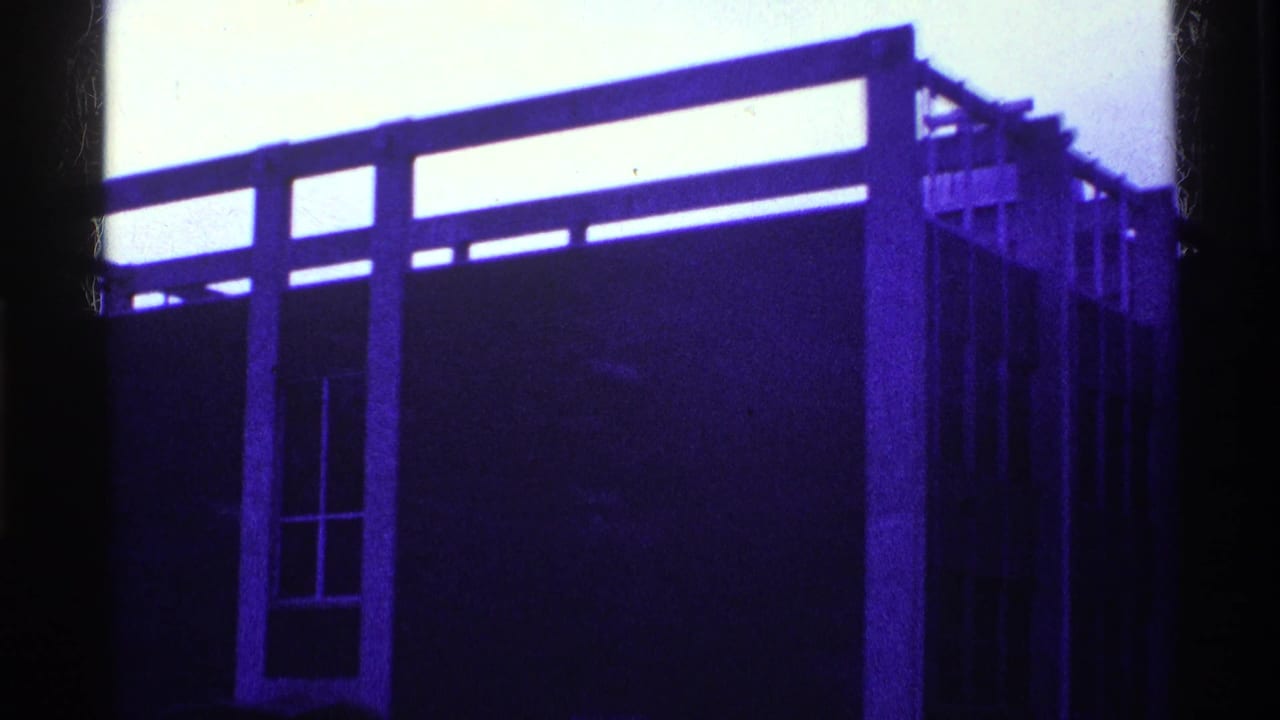 Blue-purple building facade with upper rail, narrow window, and dark center frame.