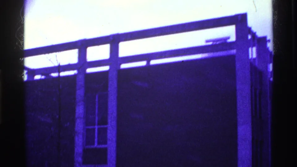 1969 Ohio 8mm frame showing the building from another angle, with a large wall plane, vertical supports, and a tall window opening.