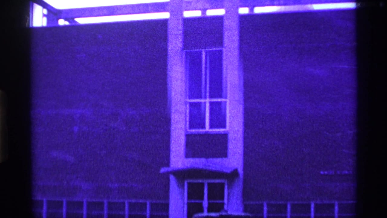 1969 Ohio 8mm frame showing a purple-tinted modernist building facade with rectangular windows and a dark foreground obstruction.