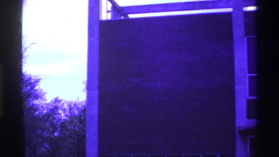 1969 Ohio 8mm frame showing a modernist exterior corner, partial windows, bare trees, and a strong purple-blue cast.