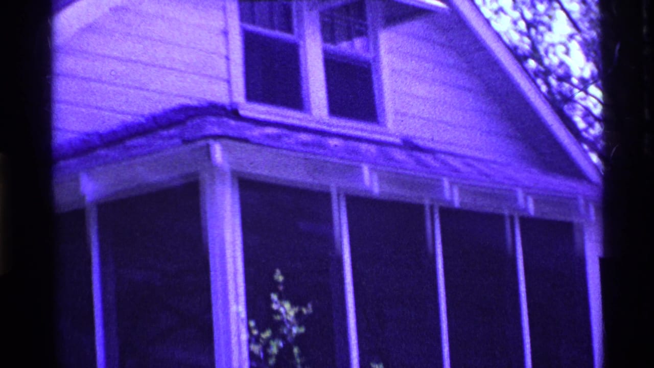 Purple-tinted house corner with upper windows and screened porch below.