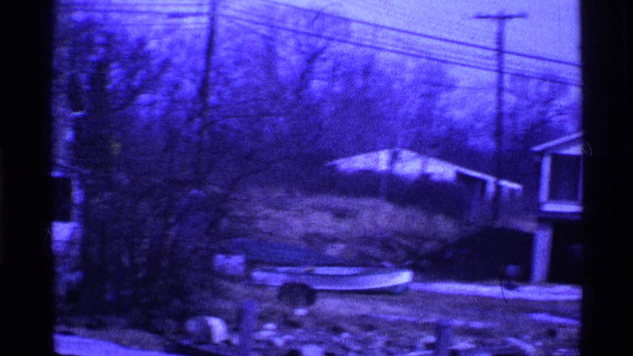 1969 Ohio 8mm frame showing a snowy suburban yard, small boat on the lawn, outbuilding, bare trees, and overhead wires.