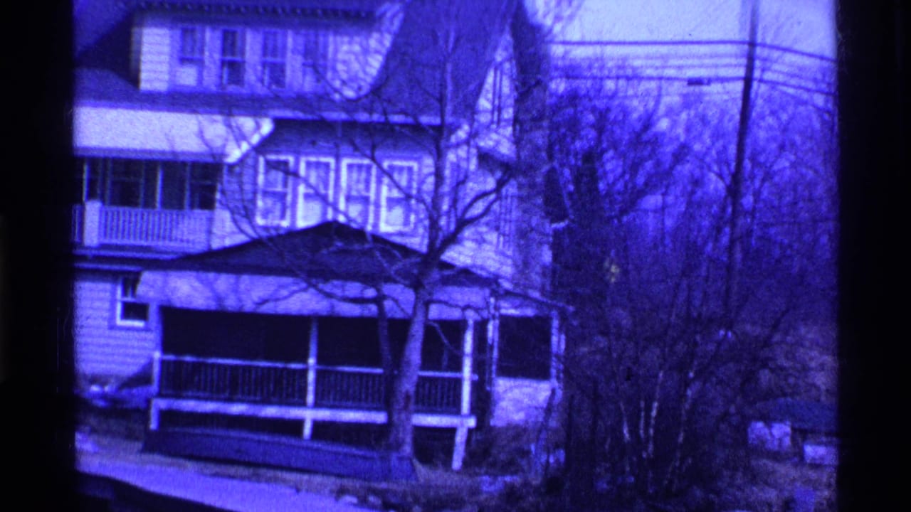 Two-story house with porch, bare trees, snow patches, and utility lines.