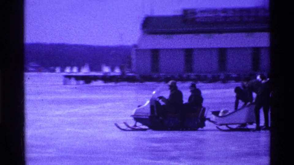 In the final frame, seated riders move across the Ohio lake ice on a sled, with another sled and shoreline structure visible behind them.