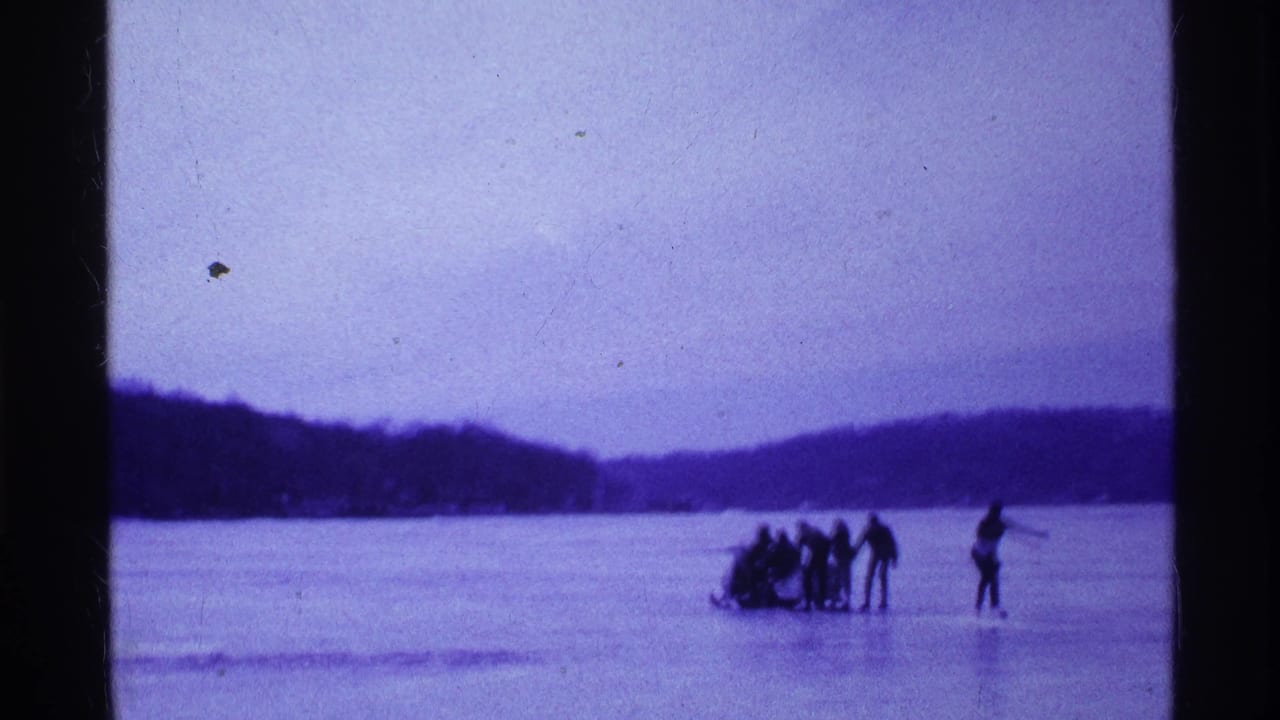 1969 Ohio footage shows a distant group with a sled on the frozen lake while one person stands slightly away on the ice.