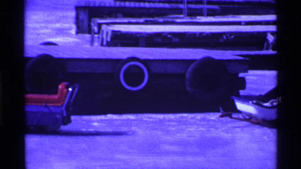 1969 Ohio winter frame showing a red-seated sled in the foreground and a large dark vehicle beyond it on frozen ground.
