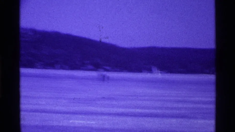 1969 Ohio 8mm view of a calm lake with a distant tree-lined shore and strong purple-blue film cast.