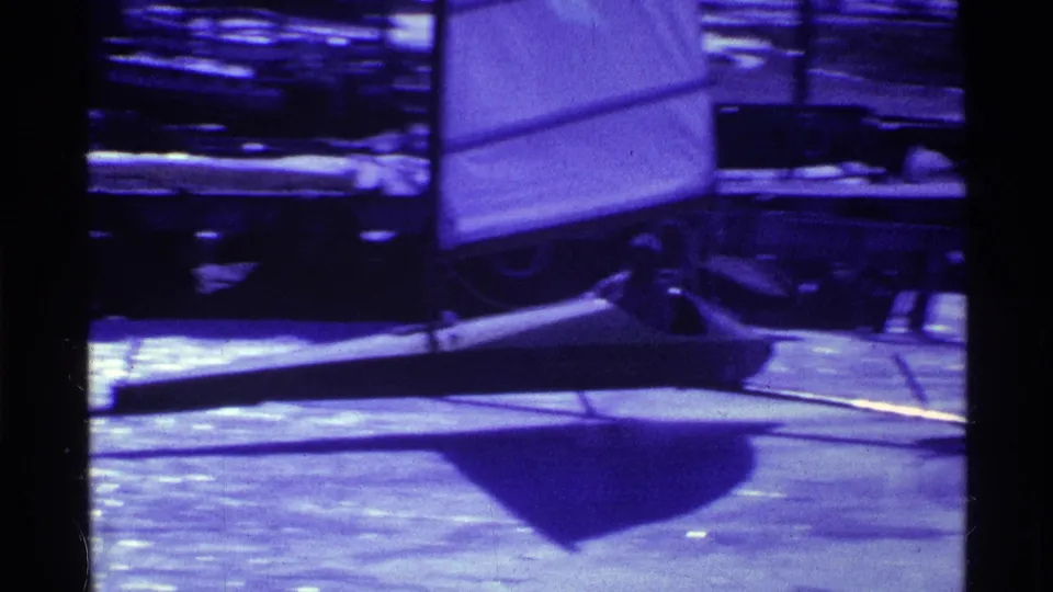 1969 Ohio 8mm frame with a seated person in a low ice boat or sail sled on a frozen lake.
