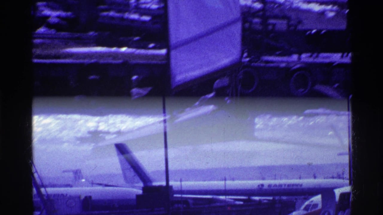 Passenger jet seen through an airport window with dark mullions and a purple sky.
