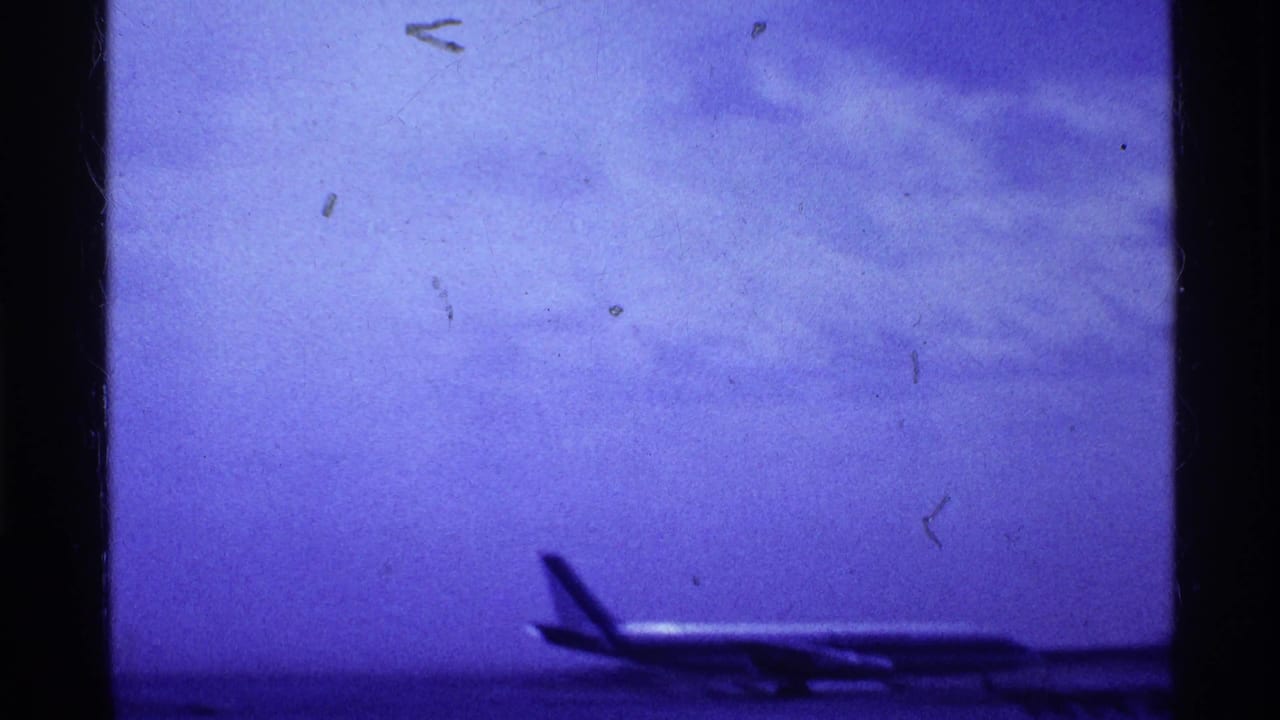 Distant aircraft silhouette on a runway beneath a blue-purple cloudy sky.