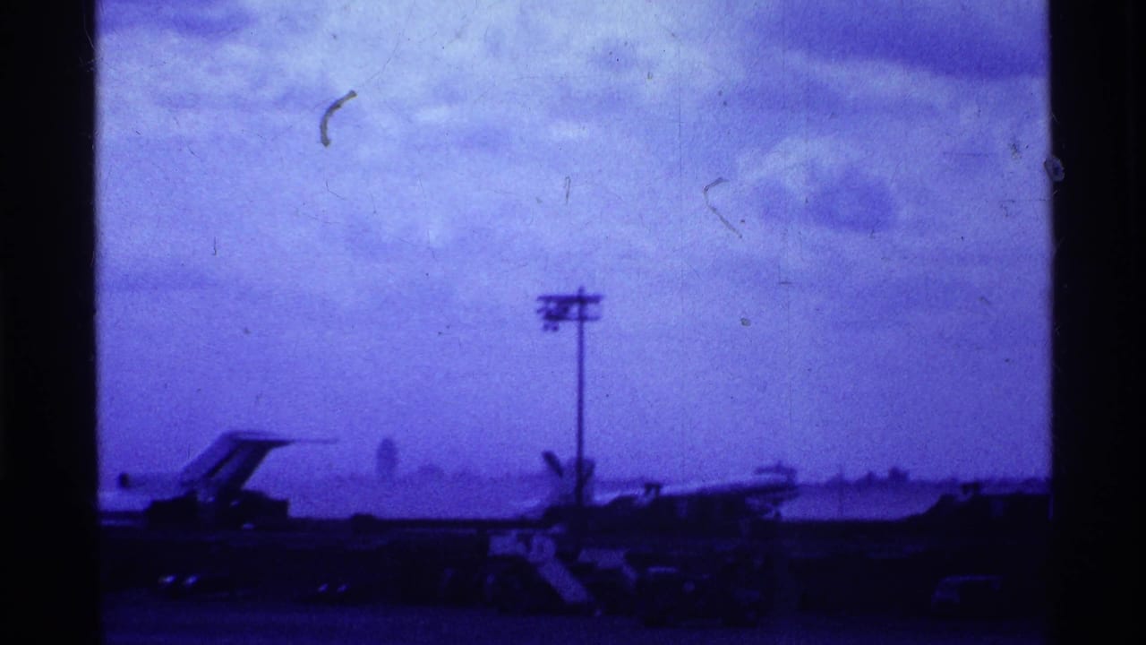 Airliner on the runway with light pole and cloudy sky behind dark frame bars.