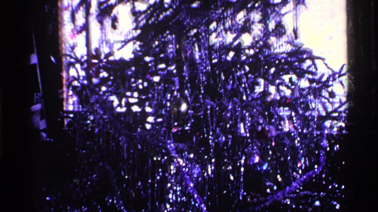 Tinsel Christmas tree filling a dark interior frame.