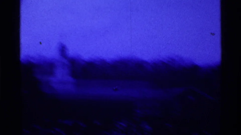 End frame from the 1969 Ohio football clip, with blurred field action, dark tree line, and blue-tinted sky.