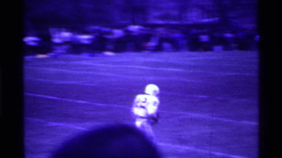White-uniformed football player number 22 runs in open field during a 1969 Ohio home-movie football sequence.