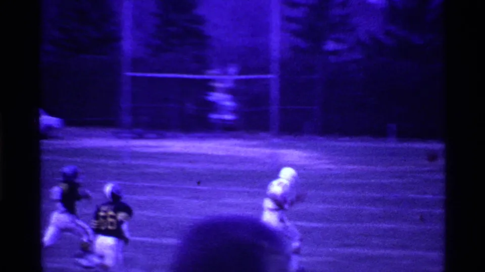 1969 Ohio football frame showing a white-uniformed runner ahead of dark-uniformed defenders near the far side of the field.