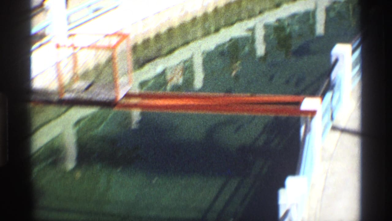 Dark water below a bridge with red railing and pale concrete posts at the edge of the frame.