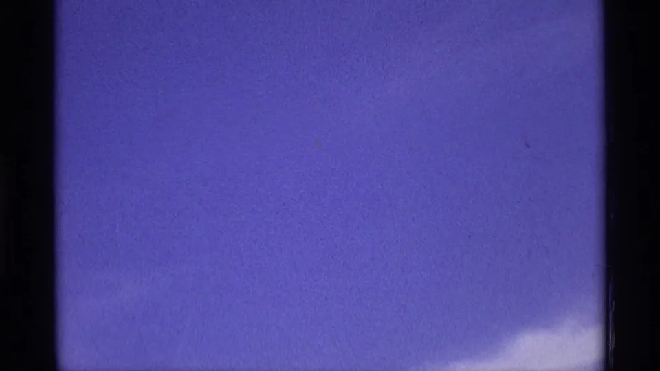 Metadata-supported 1970 8mm home-movie frame with open blue sky, a small white cloud at the lower right, visible film edge, and soft grain.