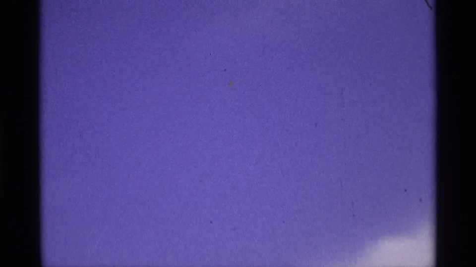 Metadata-supported 1970 8mm home-movie frame with blue sky, a soft white cloud at the lower right, dark scan borders, and subtle specks in the film image.