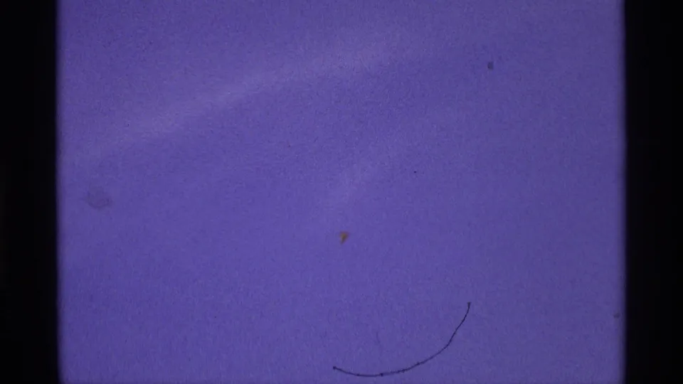 The clip ends on a purple-tinted 8mm film frame with visible scratches, dust, and little discernible subject detail.