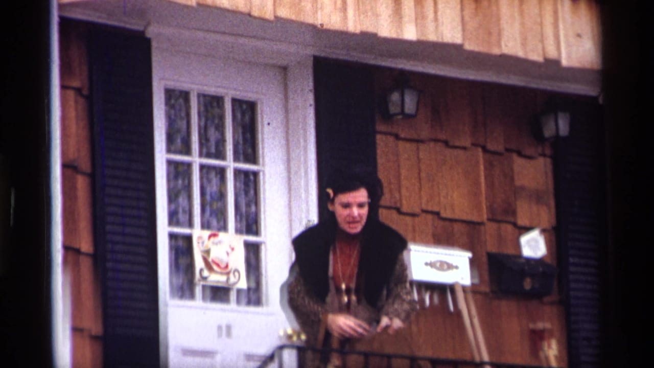 Woman standing on a stoop beside a white door with black shutters and wood siding.