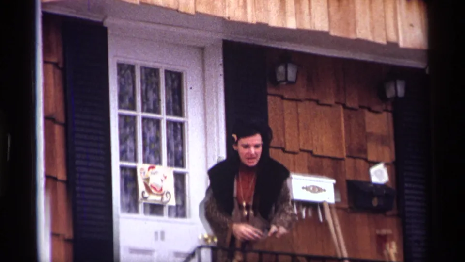 Adult woman on a New York City residential stoop in 1970, with a Santa decoration on the white door behind her.
