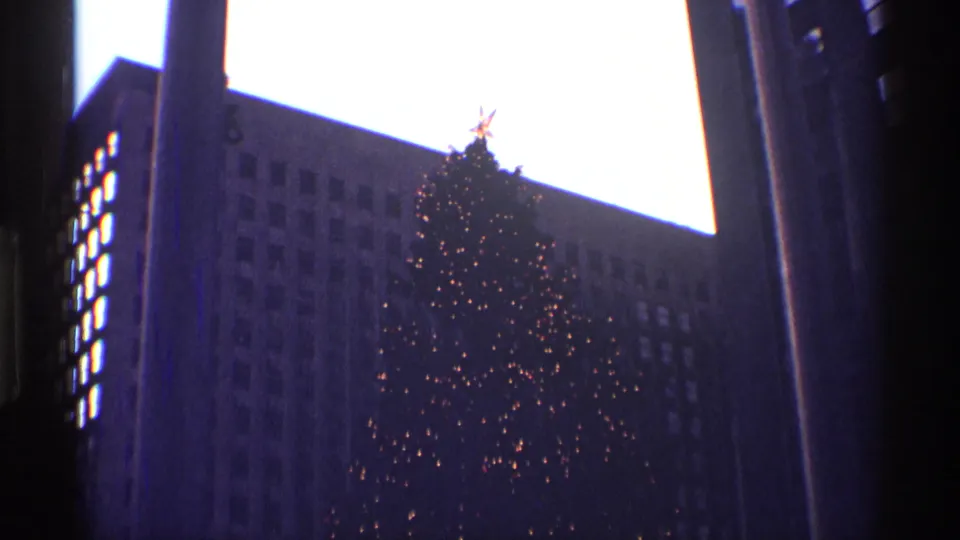 1970 Rockefeller Center Christmas tree with warm lights, a bright star topper, and dark city buildings around it.