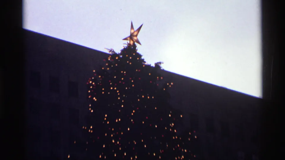 1970 Rockefeller Center holiday view with the tree's glowing star and lights partly framed by a dark vertical foreground shape.