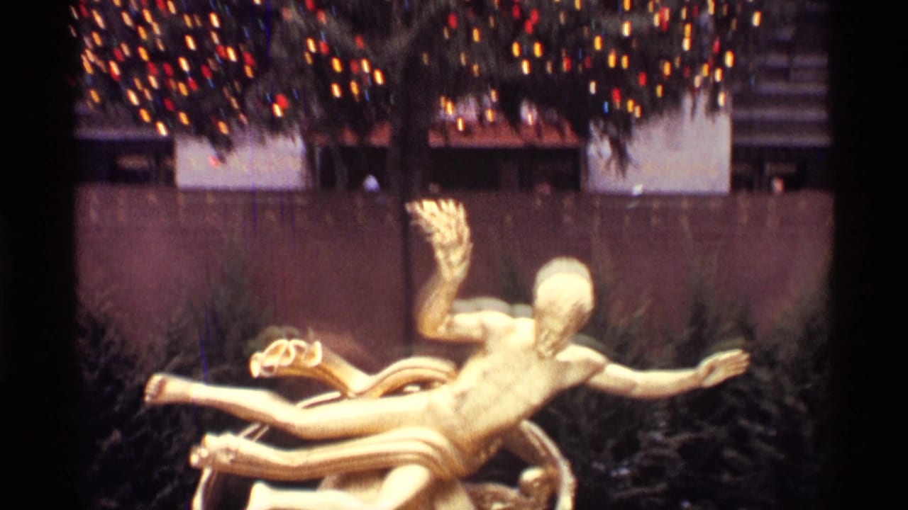 Gold reclining statue in front of a lit Christmas tree and stone building facade.