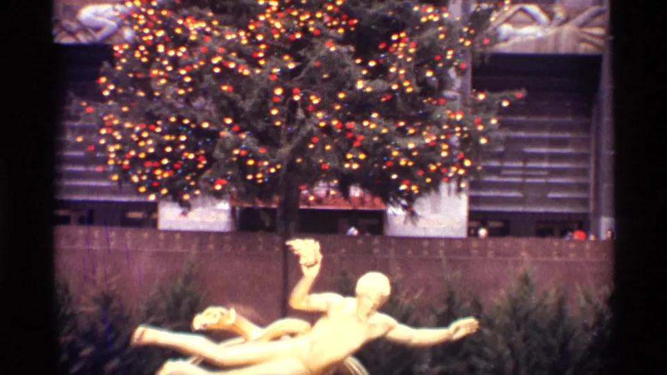 The Rockefeller Center Christmas tree fills the upper frame while a gold statue appears below in 1970 New York City footage.