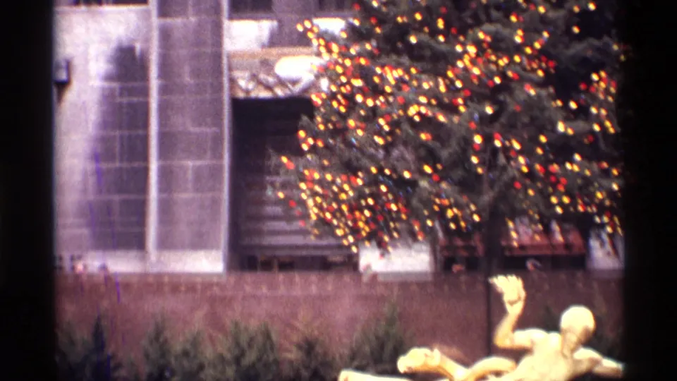 1970 New York City frame with the lit Christmas tree above the golden Prometheus statue in Rockefeller Center plaza.