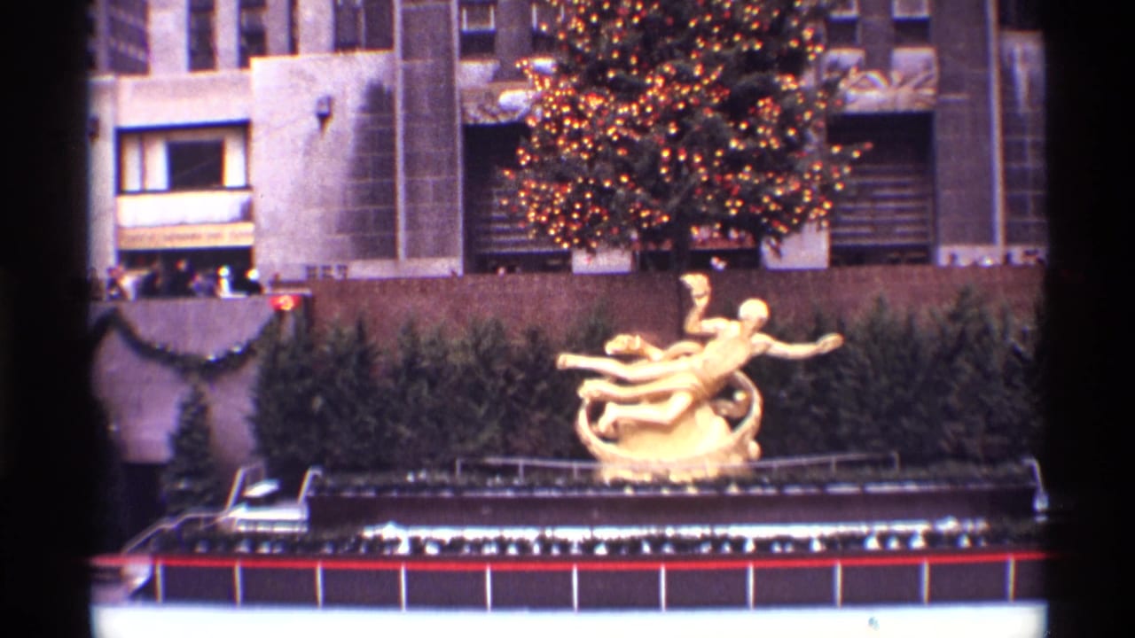 1970 New York City 8mm frame overlooking the Rockefeller Center rink area with Prometheus sculpture and lit holiday tree behind it.