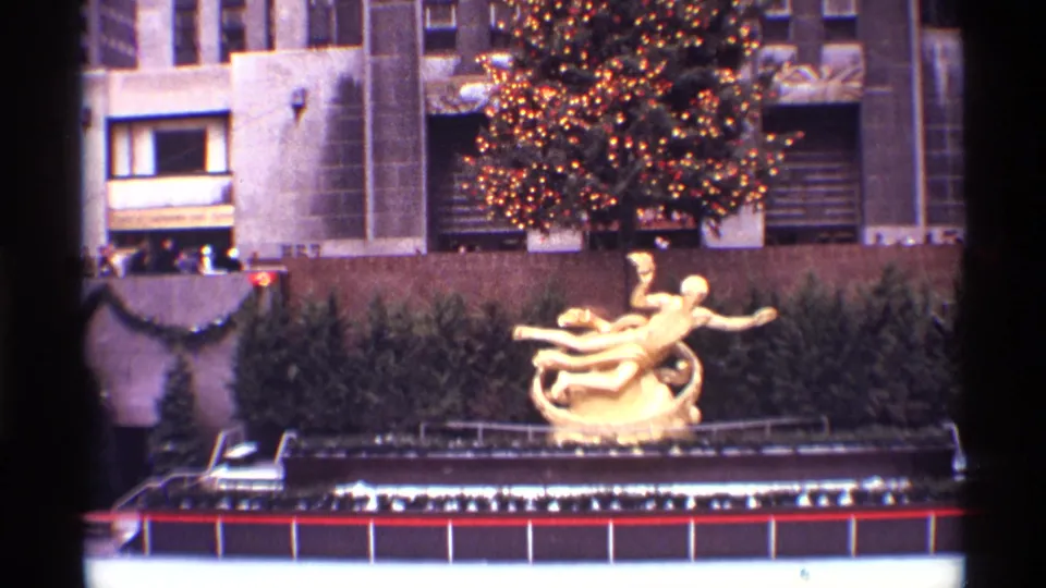 1970 New York City 8mm frame overlooking the Rockefeller Center rink area with Prometheus sculpture and lit holiday tree behind it.