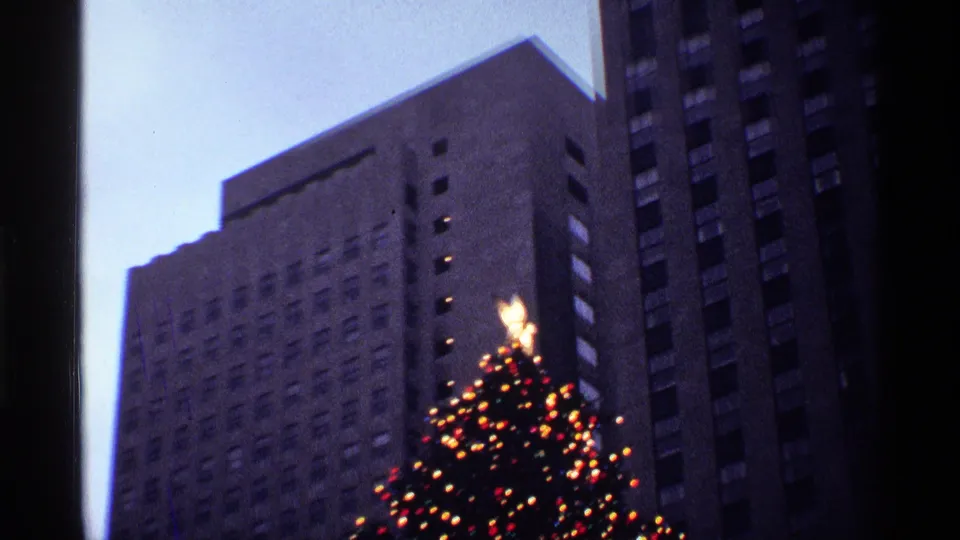 The zoom moves closer to the lit star atop the Christmas tree, with New York City high-rises behind it.