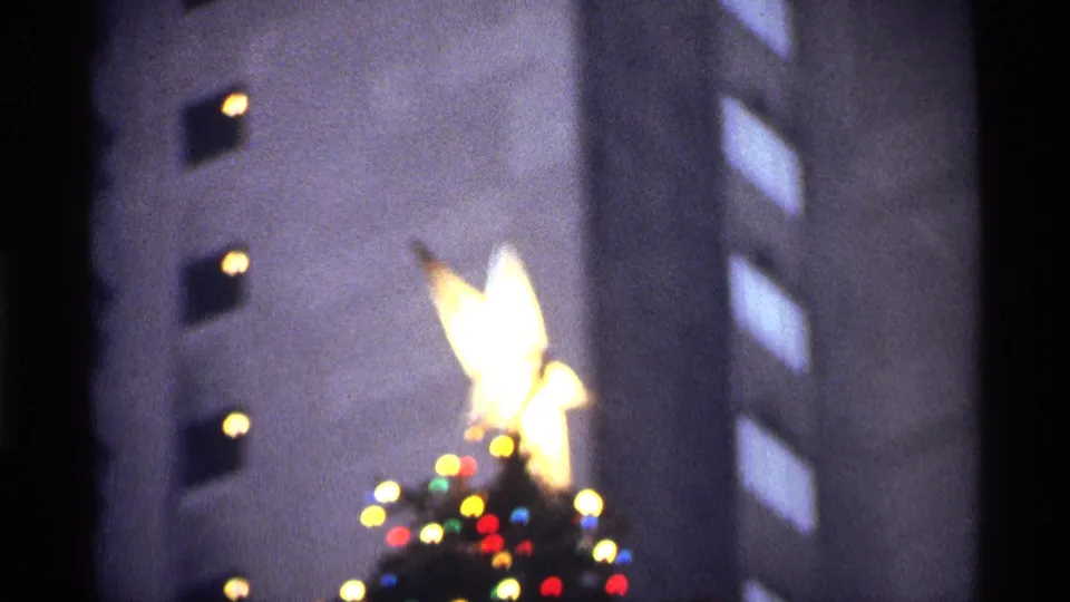 The final close view softens into the bright star and colored bulbs, with nearby building windows blurred behind.