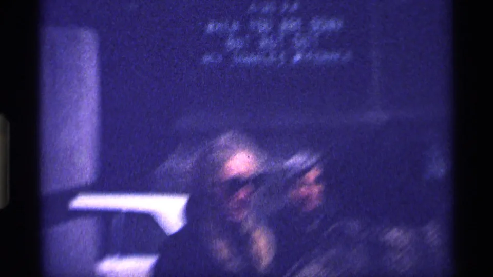 Blurred 8mm frame from the clip opening, showing a soft human figure near a vertical architectural edge in New York City metadata context.