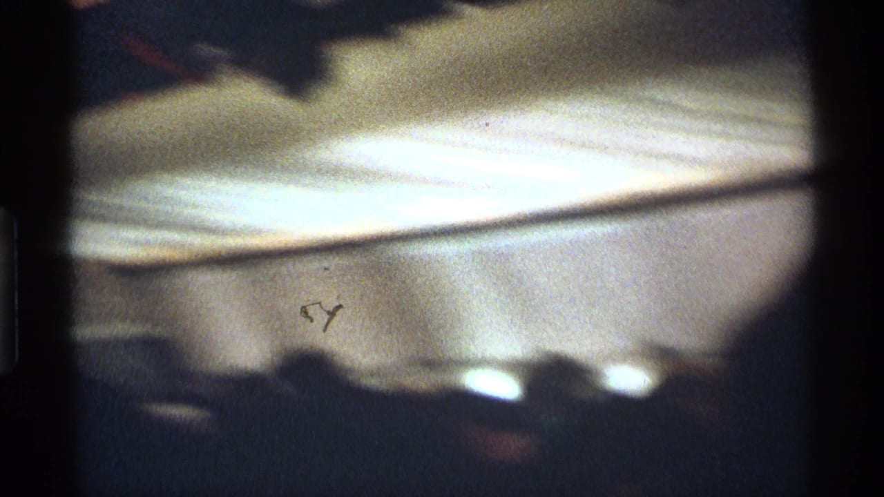 Soft, dark view of airplane cabin ceiling and passenger silhouettes below the overhead panels.