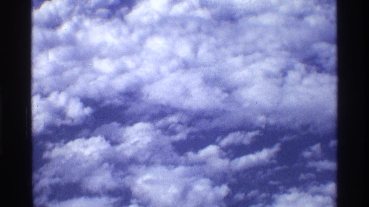 Cloud tops seen through a dark airplane window frame.