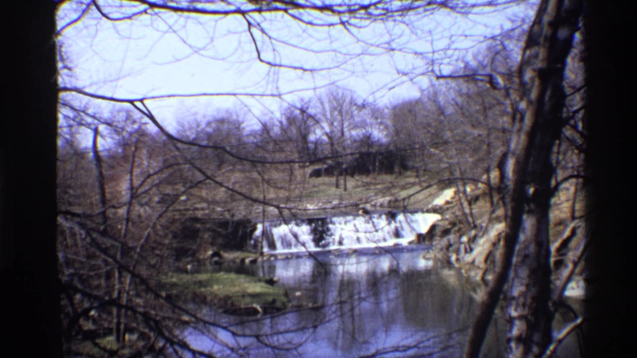 1971 New York City 8mm view of a small waterfall and river framed by leafless trees in a winter landscape.
