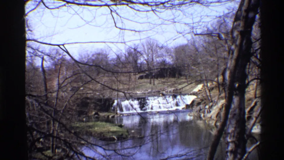 1971 New York City 8mm view of a small waterfall and river framed by leafless trees in a winter landscape.