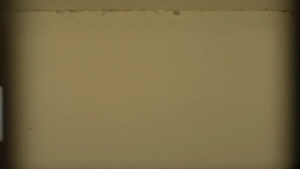 A blank or overexposed 8mm film frame with yellowish tone, dark gate edges, and visible dust specks.