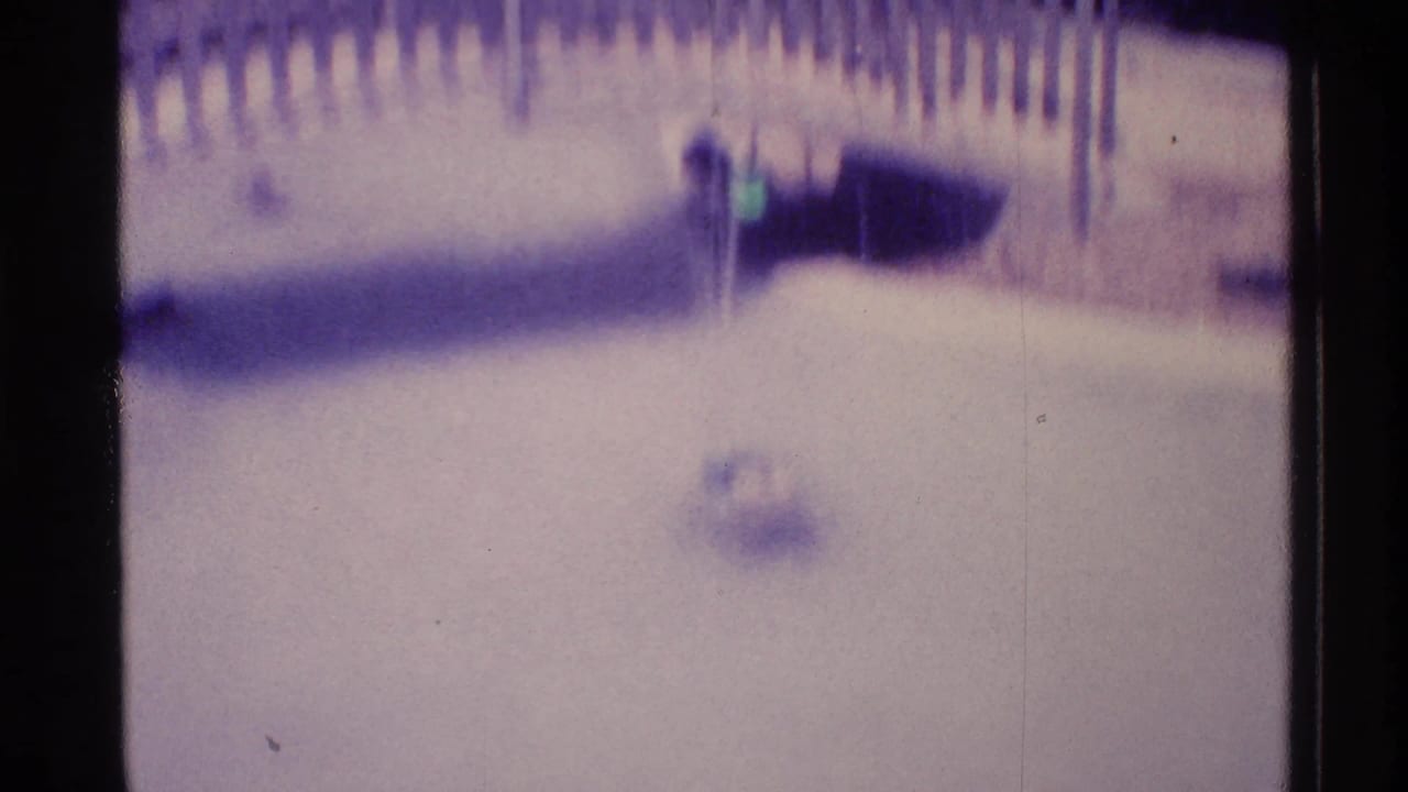 Soft 8mm view of fountain water with a curved bridge or railing in the background.