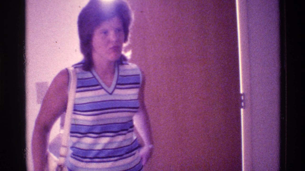 Woman in a striped sleeveless top stands by a doorway with a white shoulder bag.