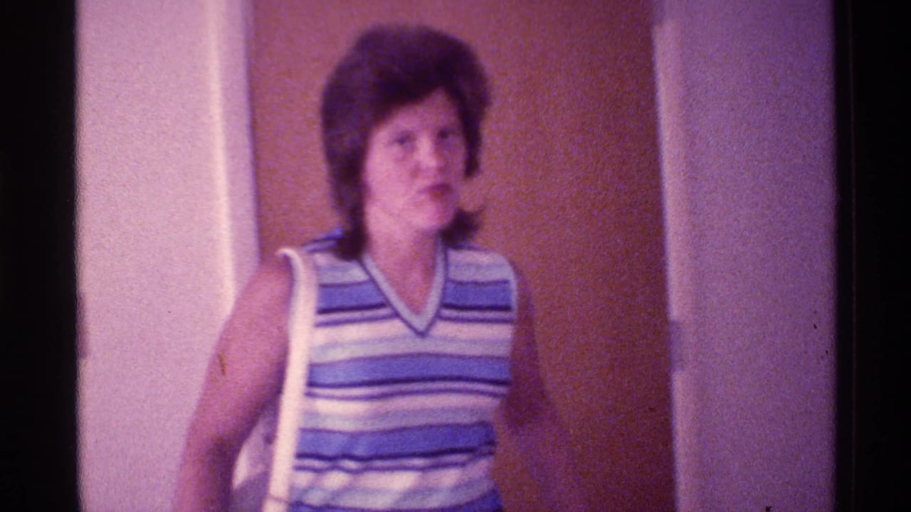 Woman in striped sleeveless top walks past a brown interior door.