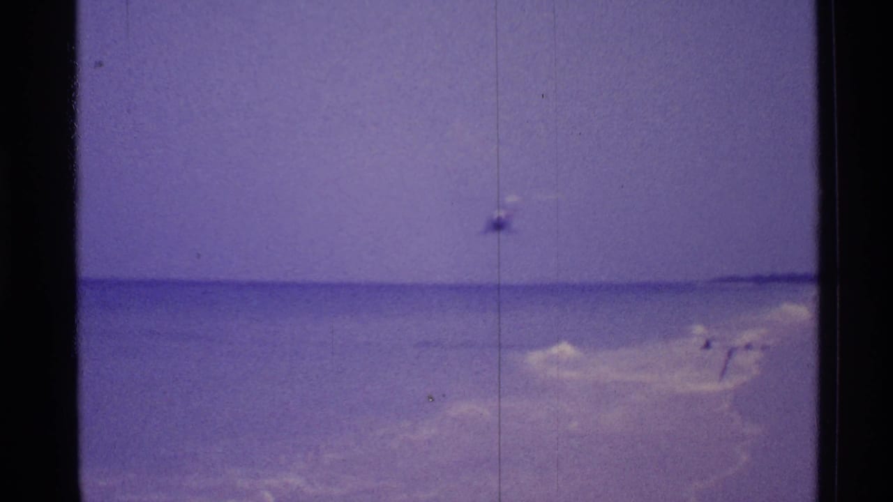 Helicopter appears over the ocean near a Florida beach with film borders visible.