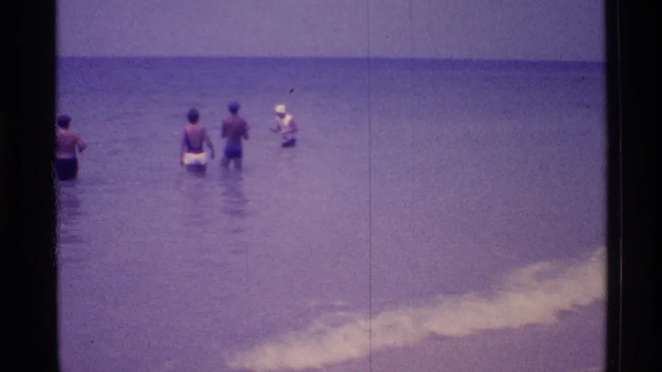 1973 Florida beach home-movie view of people wading near shore with pale surf breaking in the foreground.