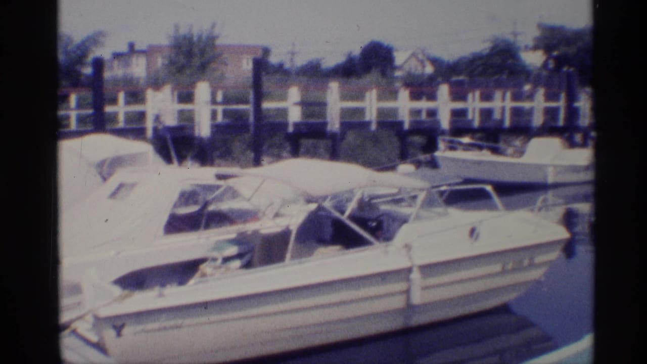 White motorboats docked at a marina beside a railing and calm water.